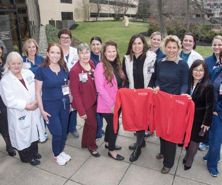 Group of nurses with two nurses holding red Temple sweatshirts
