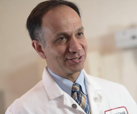 A closeup photo of a Fox Chase doctor speaking to someone off camera while in a medical room, smiling.