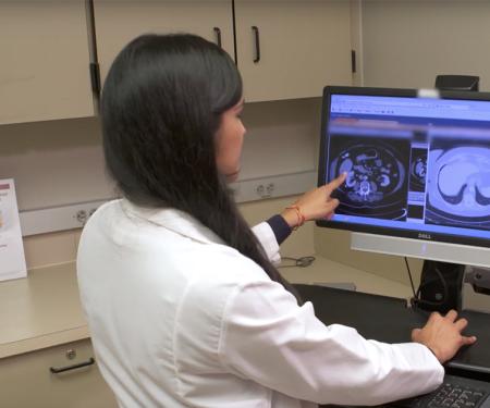 A photograph looking over the shoulders of two people as they look at medical imaging results on a screen.